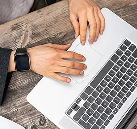 person typing on a laptop on a wooden table